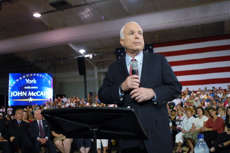 Sen. John McCain at a podium in front of a crowd and an American flag.